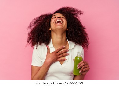 Young African American Woman Drinking A Healthy Smoothie Isolated On Pink Background Laughs Out Loudly Keeping Hand On Chest.