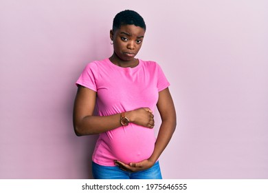 Young african american woman expecting a baby, touching pregnant belly depressed and worry for distress, crying angry and afraid. sad expression. 