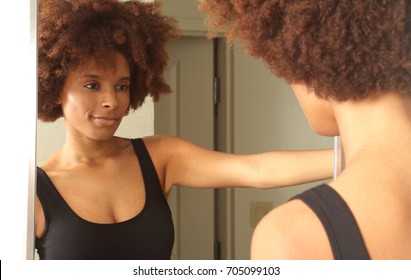 Young African American Woman Getting Ready For Work In Mirror