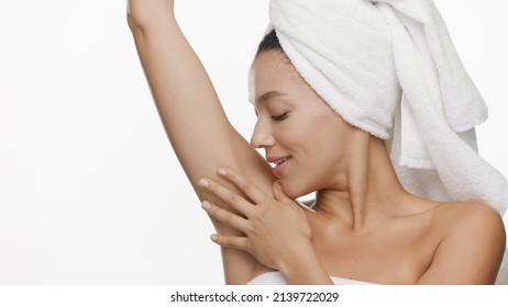 Young African American woman in hari drying towel raises arm and touches her smooth armpit on white background | Unwanted hair or antiperspirant commercial concept - Powered by Shutterstock