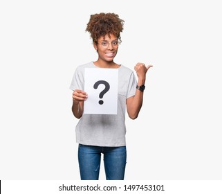 Young african american woman holding paper with question mark over isolated background pointing and showing with thumb up to the side with happy face smiling - Powered by Shutterstock