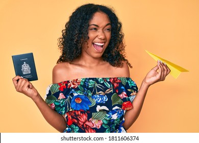 Young African American Woman Holding Paper Airplane And Canadian Passport Angry And Mad Screaming Frustrated And Furious, Shouting With Anger. Rage And Aggressive Concept. 