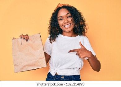 Young African American Woman Holding Take Away Paper Bag Smiling Happy Pointing With Hand And Finger 