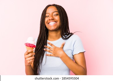 Young african american woman holding an ice cream isolated laughs out loudly keeping hand on chest.