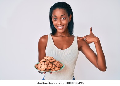 Young African American Woman Holding Plate With Cookies Pointing Finger To One Self Smiling Happy And Proud 