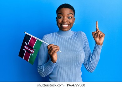 Young african american woman holding kenya flag smiling with an idea or question pointing finger with happy face, number one 