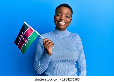 Young african american woman holding kenya flag looking positive and happy standing and smiling with a confident smile showing teeth 