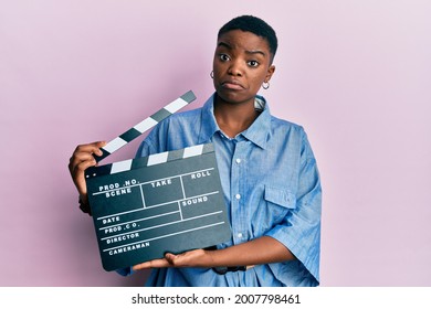 Young African American Woman Holding Video Film Clapboard Clueless And Confused Expression. Doubt Concept. 