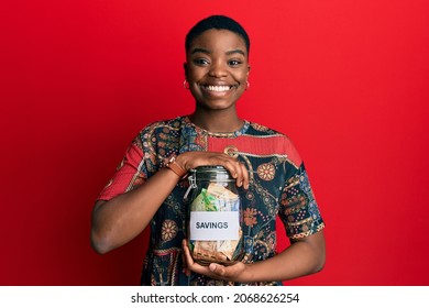 Young African American Woman Holding Savings Jar With South African Rands Money Smiling With A Happy And Cool Smile On Face. Showing Teeth. 