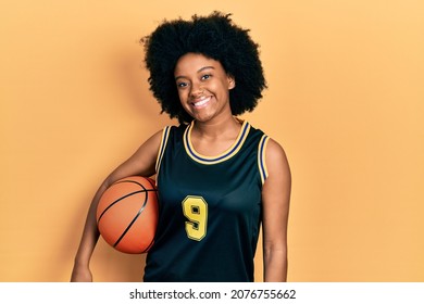 Young african american woman holding basketball ball looking positive and happy standing and smiling with a confident smile showing teeth  - Powered by Shutterstock