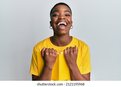 Young African American Woman Holding Book Smiling And Laughing Hard Out Loud Because Funny Crazy Joke. 