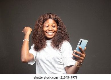 Young African American Woman Holding Mobile Phone Screaming Proud, Celebrating Victory And Success Very Excited With Raised Arm