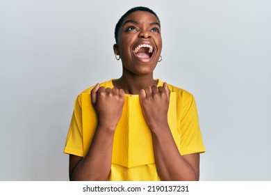 Young African American Woman Holding Book Angry And Mad Screaming Frustrated And Furious, Shouting With Anger Looking Up. 