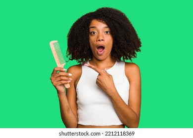 Young African American Woman Holding Hair Comb Isolated Pointing To The Side