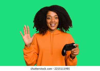 Young African American Woman Holding A Game Controller Isolated Smiling Cheerful Showing Number Five With Fingers.