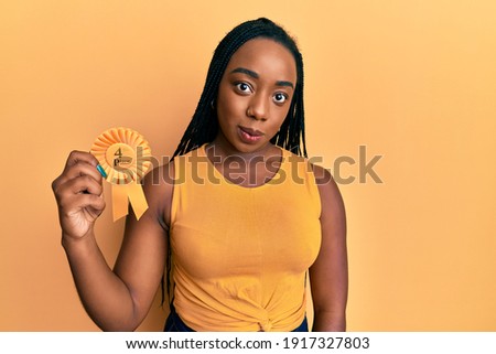 Young african american woman holding fourth place badge thinking attitude and sober expression looking self confident 