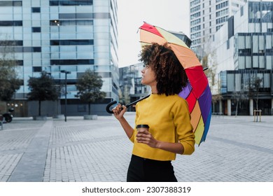 young African American woman homosexual with rainbow flag or umbrella in city of Latin America, Hispanic and caribbean LGBT female with afro hair 
