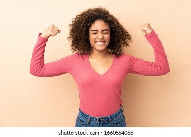 Young African American woman isolated on beige background doing strong gesture