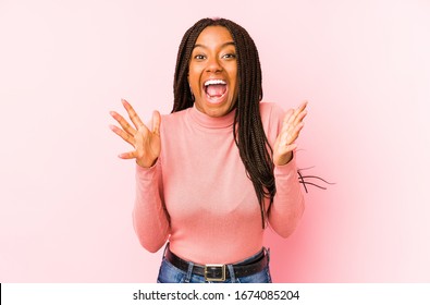 Young african american woman isolated on a pink background celebrating a victory or success, he is surprised and shocked.