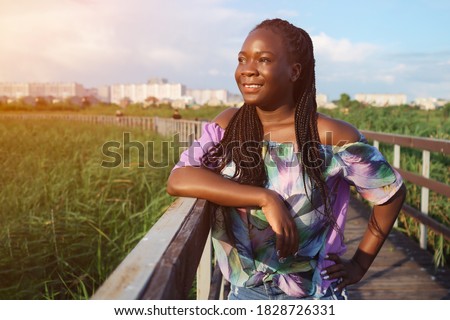Young african american woman leaning on the handrail of the bridge and looking away, copy space