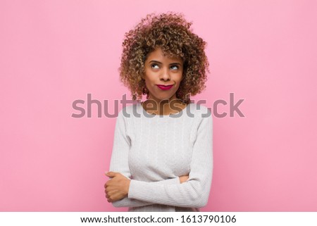 young african american woman looking goofy and funny with a silly cross-eyed expression, joking and fooling around against pink wall