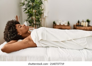 Young african american woman lying on massage table at beauty center