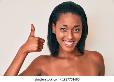 Young african american woman naked over background smiling happy and positive, thumb up doing excellent and approval sign 
