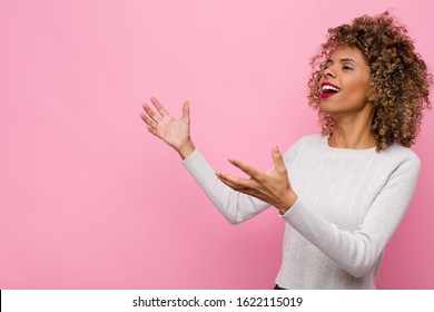 young african american woman performing opera or singing at a concert or show, feeling romantic, artistic and passionate against pink wall