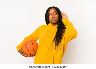 Young African American Woman Playing Basketball Isolated Trying To Listening A Gossip.