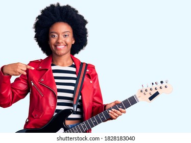 Young african american woman playing electric guitar pointing finger to one self smiling happy and proud 