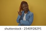 Young african american woman pointing sideways against a yellow background