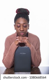 A Young African American Woman Praying Over The Holy Bible