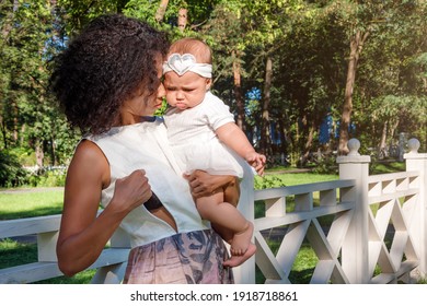 Young African American Woman Preparing For Breastfeeding Her Baby In Summer Park. Black Mother Breast Feeding Her Child. Infancy, Motherhood, Lactation, Nutrition And Outdoor Breastfeeding Concept.