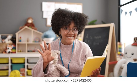 Young african american woman preschool teacher reading story book at kindergarten - Shutterstock ID 2273422405