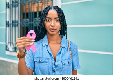 Young African American Woman With Relaxed Expression Holding Pink Breast Cancer Ribbon At The City.