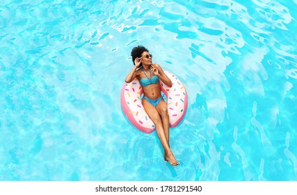 Young African American Woman Relaxing On Donut Inflatable Ring In Hotel Resort Pool, Overhead View. Panorama