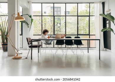 Young African American Woman Relaxing. Sitting Behind Desk Writing Notes. Legs Up On The Table. Spacious Loft Apartment.