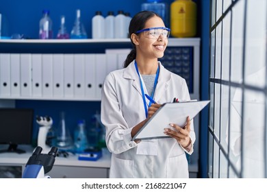 Young african american woman scientist write on report document at laboratory - Shutterstock ID 2168221047