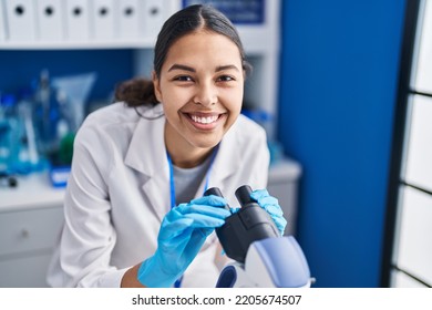 Young African American Woman Scientist Using Microscope At Laboratory