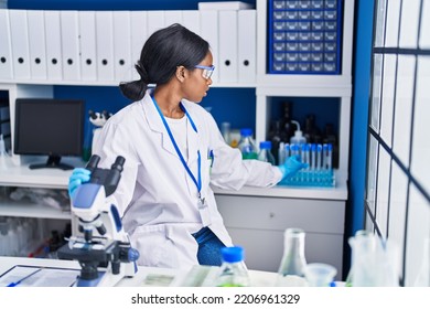 Young African American Woman Scientist Using Microscope Working At Laboratory