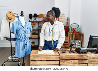 Young African American Woman Shopkeeper Writing On Notebook At Clothing Store