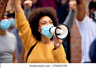Young African American woman shouting through megaphones while supporting anti-racism protests.  - Shutterstock ID 1754251790