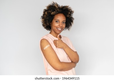 Young African American Woman Showing Thumb Up And Her Arm With Band Aid After Coronavirus Covid-19 Vaccine Injection. Covid Vaccination Concept