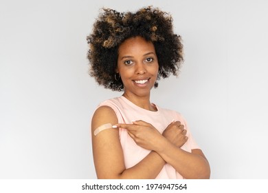 Young African American Woman Showing Her Arm With Band Aid After Coronavirus Covid-19 Vaccine Injection. Covid Vaccination Concept