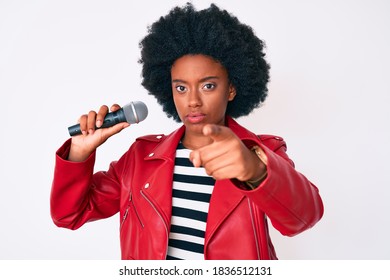 Young African American Woman Singing Song Using Microphone Pointing With Finger To The Camera And To You, Confident Gesture Looking Serious 