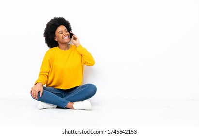 Young African American woman sitting on the floor keeping a conversation with the mobile phone - Powered by Shutterstock