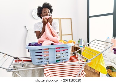 Young african american woman smelling clothes doing laundry at laundry - Powered by Shutterstock