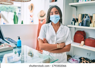 Young African American Woman Smiling Happy Working At The Till Wearing Coronavirus Safety Mask At Retail Shop