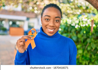 Young african american woman smiling happy holding orange awareness ribbon at the park. - Shutterstock ID 1870418371