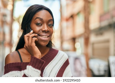 Junge afrikanische Amerikanerin lächelt glücklich über das Smartphone der Stadt.